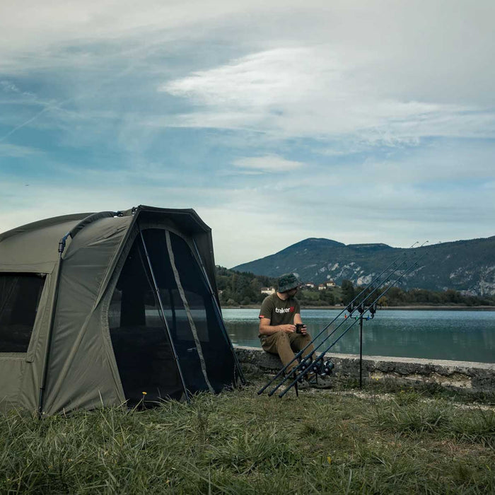 man in lake preparing for carp fishing next to tent